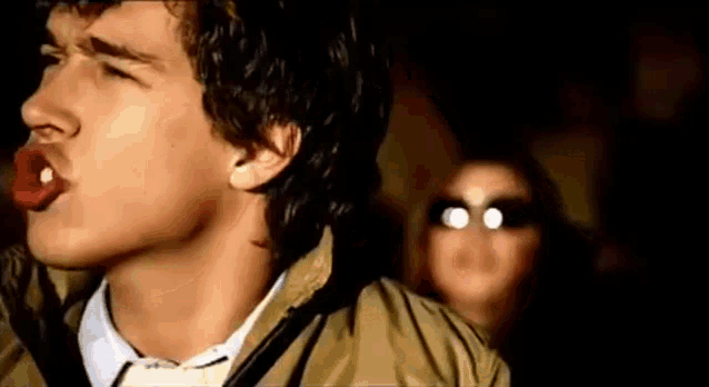 a young man is sticking his tongue out while a woman watches .