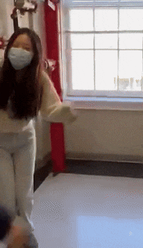 a woman wearing a mask is dancing in front of a window