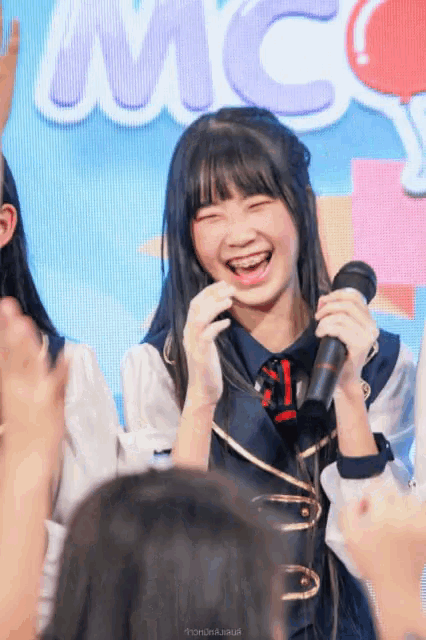 a girl laughs while holding a microphone in front of the word mc