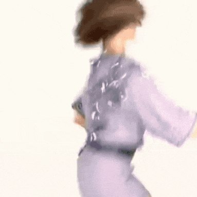 a woman in a purple shirt and pants is dancing in a blurry photo .