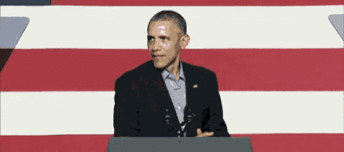 obama is giving a speech in front of an american flag .