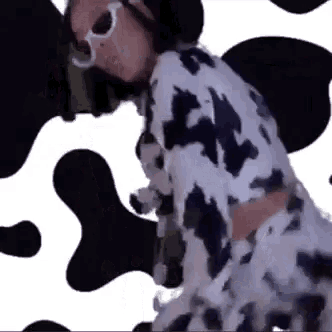 a woman in a cow print dress and sunglasses is dancing .