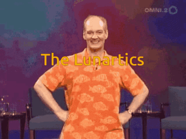 a man in an orange shirt is standing with his hands on his hips and the words the lunartics behind him