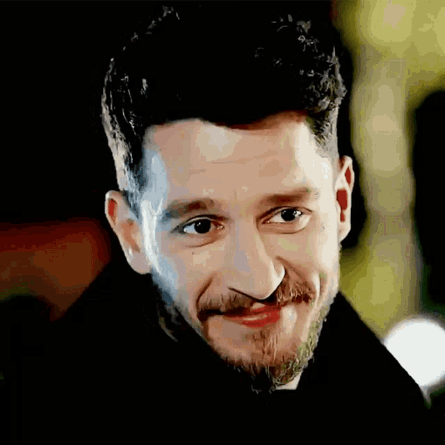 a man with a beard and mustache is smiling and looking at the camera .