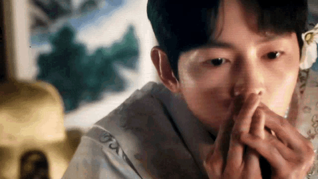 a close up of a man 's face with his hands on his mouth .