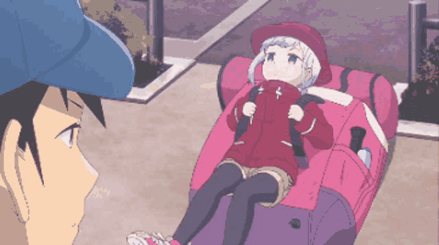 a girl in a red jacket is sitting on a pink couch