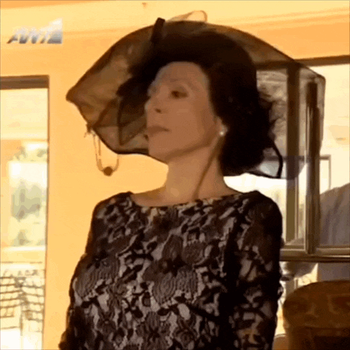 a woman wearing a black hat is standing in front of a sign that says aviz