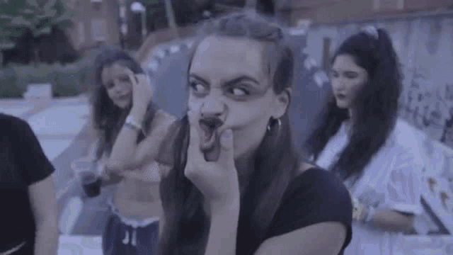 a woman is making a funny face while standing next to a group of women .
