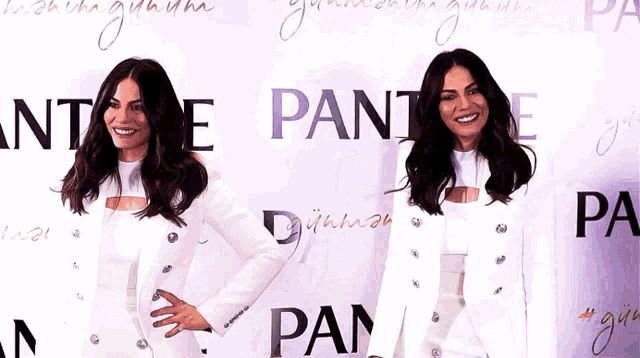 two women in white standing in front of a wall that says pantene