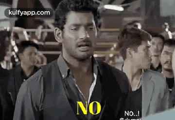 a man in a black shirt is standing in front of a crowd of people and says no .