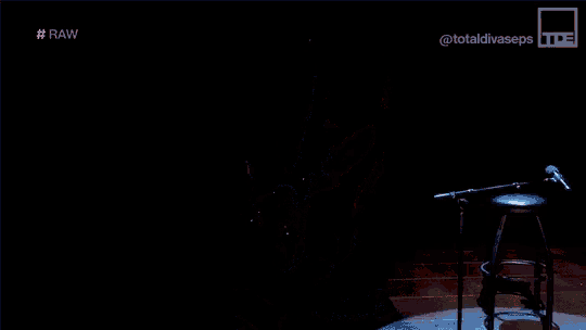 a man with a beard is playing a guitar on a stage in the dark .