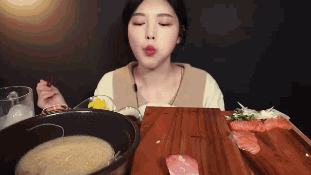 a woman is eating food with chopsticks and a bowl of soup .