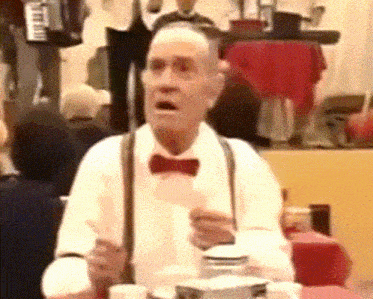 a man wearing a bow tie and suspenders holds a spoon