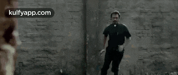 a man in a plaid shirt is walking down a street with his hands outstretched .