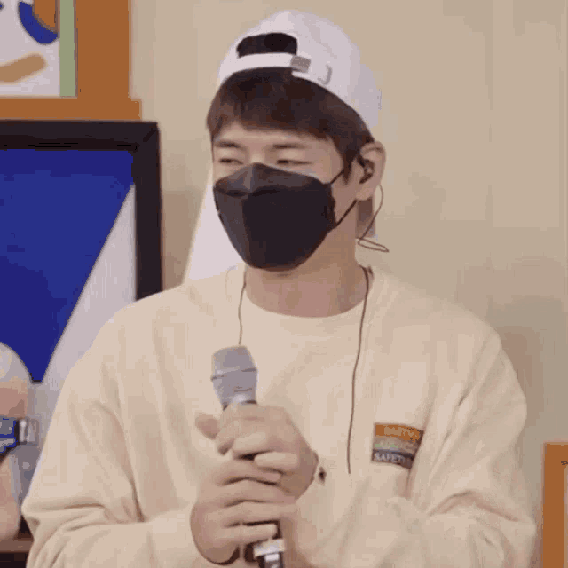 a man wearing a mask is holding a microphone .