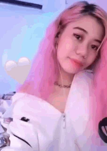a young girl with pink hair is wearing a white jacket and headphones .