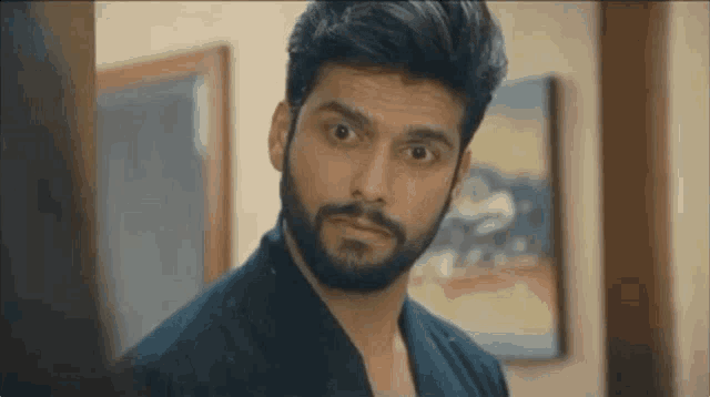 a man with a beard is looking at the camera while standing next to a woman .