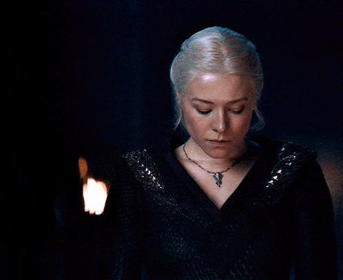 a woman in a black dress stands in front of a candle