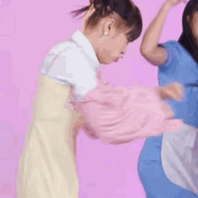 a woman in a blue dress is standing next to a girl in a pink sweater .