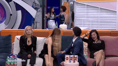 a group of people sitting on a couch with the words grande fratello on the bottom right