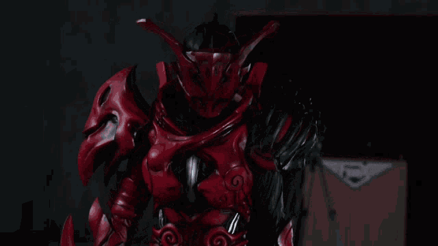 a red and black armored figure standing in front of a fender amplifier