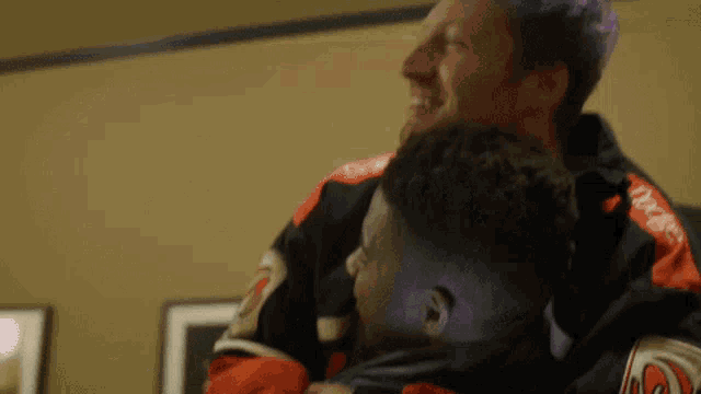 a man with purple hair is holding another man in a jersey that says devils on it