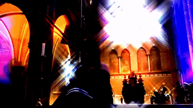 a person standing in a dark room with a purple light coming from the ceiling