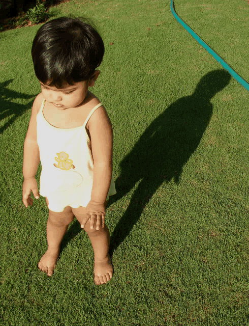 a little girl wearing a white tank top with a yellow duck on it
