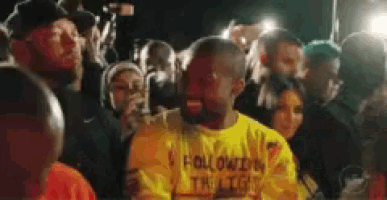 a man in a yellow shirt is surrounded by a crowd of people at a concert .