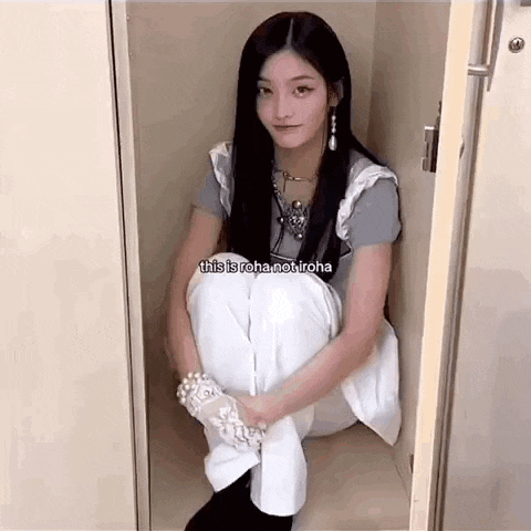 a young woman is sitting in a closet with her legs crossed .