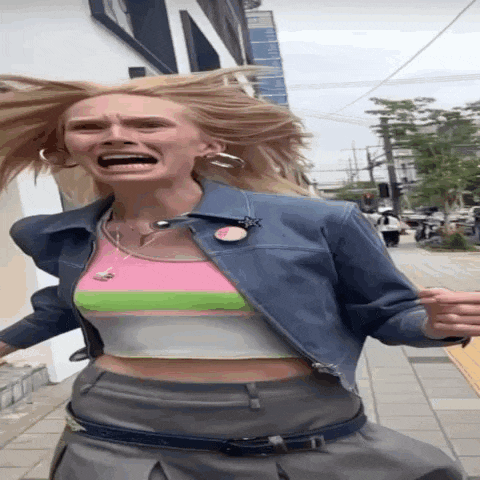 a woman wearing a crop top and a denim jacket is making a funny face with her mouth open