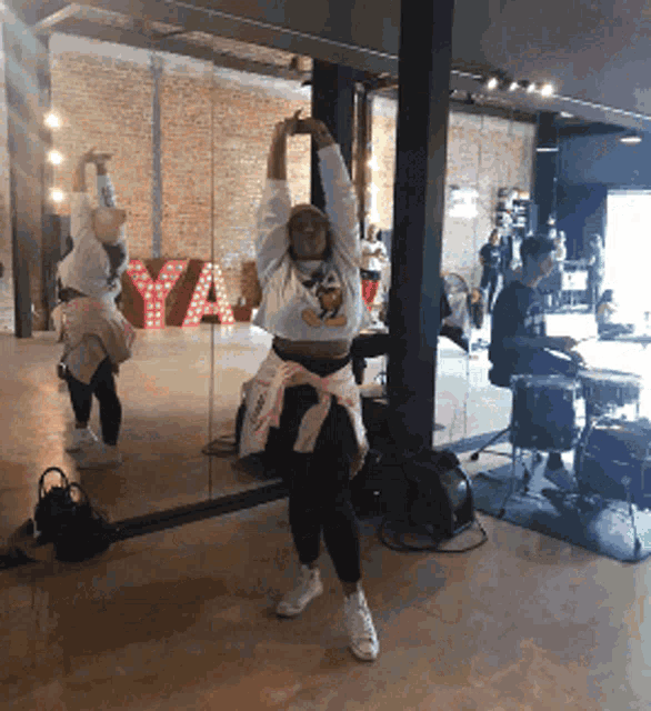 a woman is dancing in front of a mirror with a sign that says ya in the background