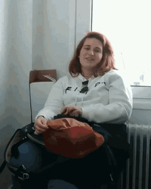 a woman wearing a white sweatshirt with rip on it