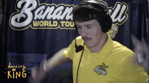 a man wearing headphones and a yellow shirt is dancing in front of a banana world tour sign