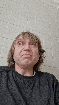 a man with long hair is wearing a gray shirt