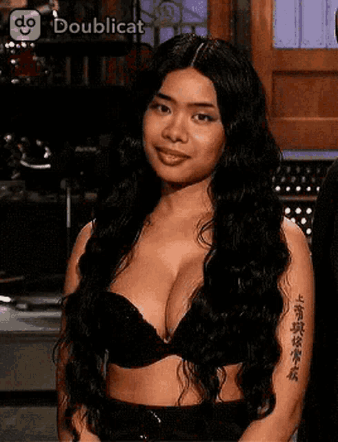 a woman with long hair and a tattoo on her arm is wearing a black bra .