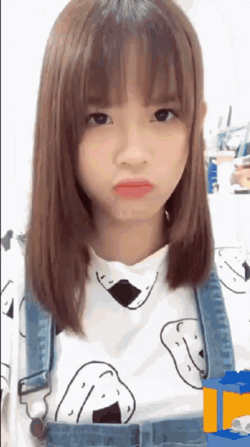a girl wearing overalls and a shirt with a cartoon face on it