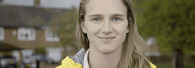 a close up of a woman 's face with a yellow jacket on