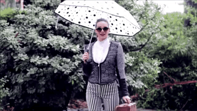 a woman holding an umbrella and a suitcase in the rain