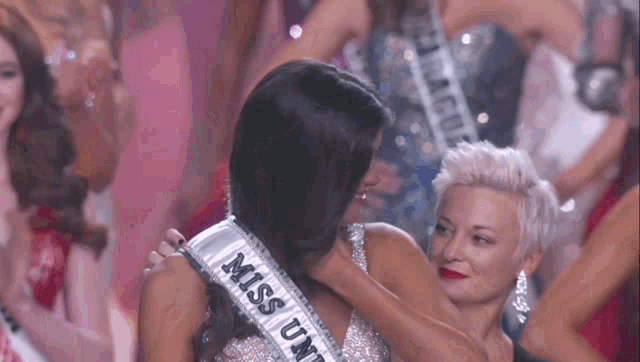 a woman wearing a sash that says miss united states is hugging another woman