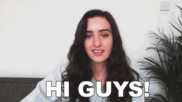 a woman is sitting on a couch and saying hi guys !