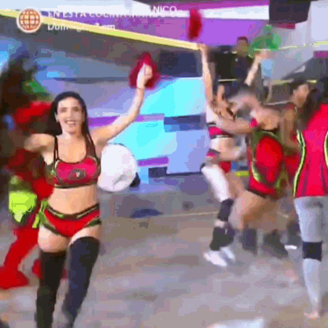 a woman in a bikini is dancing in front of a group of people .