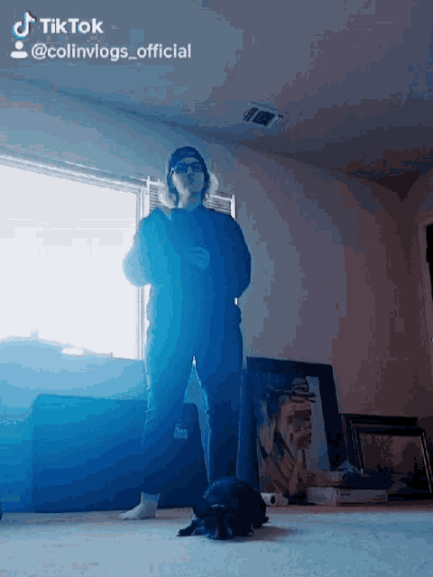 a person standing in a room with a blue light behind them that says tik tok @colinvlogs_official