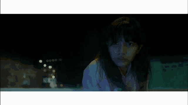 a girl with long hair is looking at something in the dark