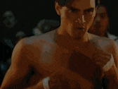 a shirtless man is standing in a boxing ring in front of a crowd of people .