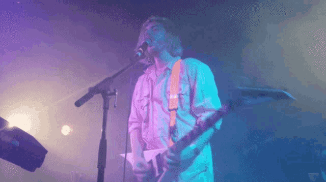 a man sings into a microphone while playing a guitar
