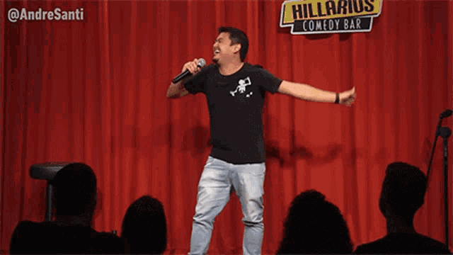 a man singing into a microphone in front of a hilarious comedy bar