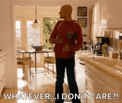 a man in a red sweater is standing in a kitchen holding a baby and a bottle .