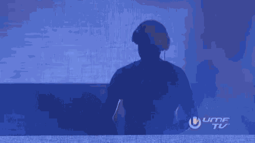 a silhouette of a man playing a dj set in front of a large screen that says umf tv