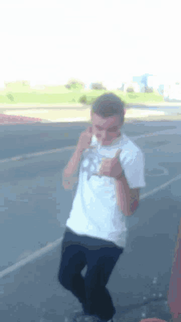a man in a white shirt is giving a thumbs up on the street